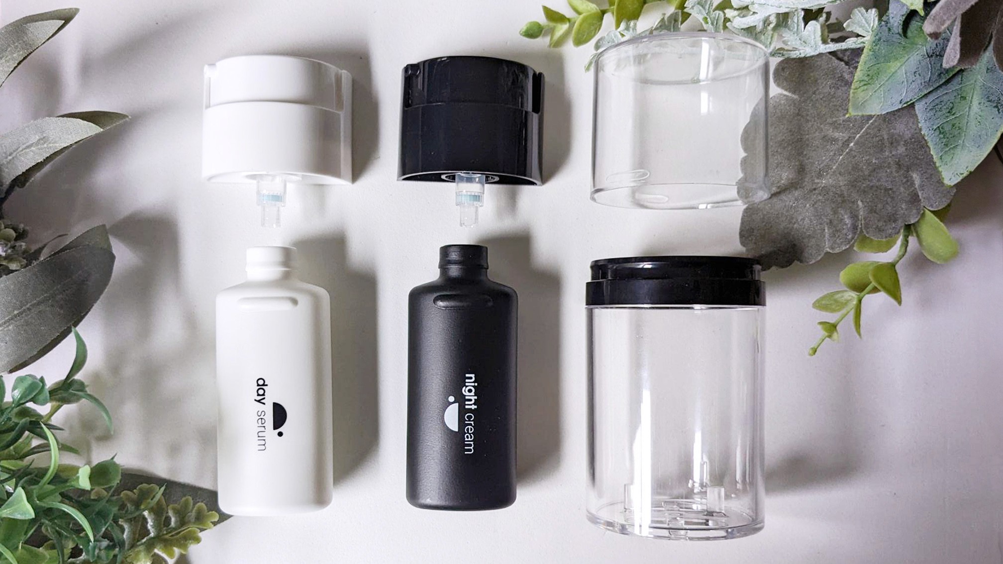 Set of reusable cosmetic containers, including white and black bottles.