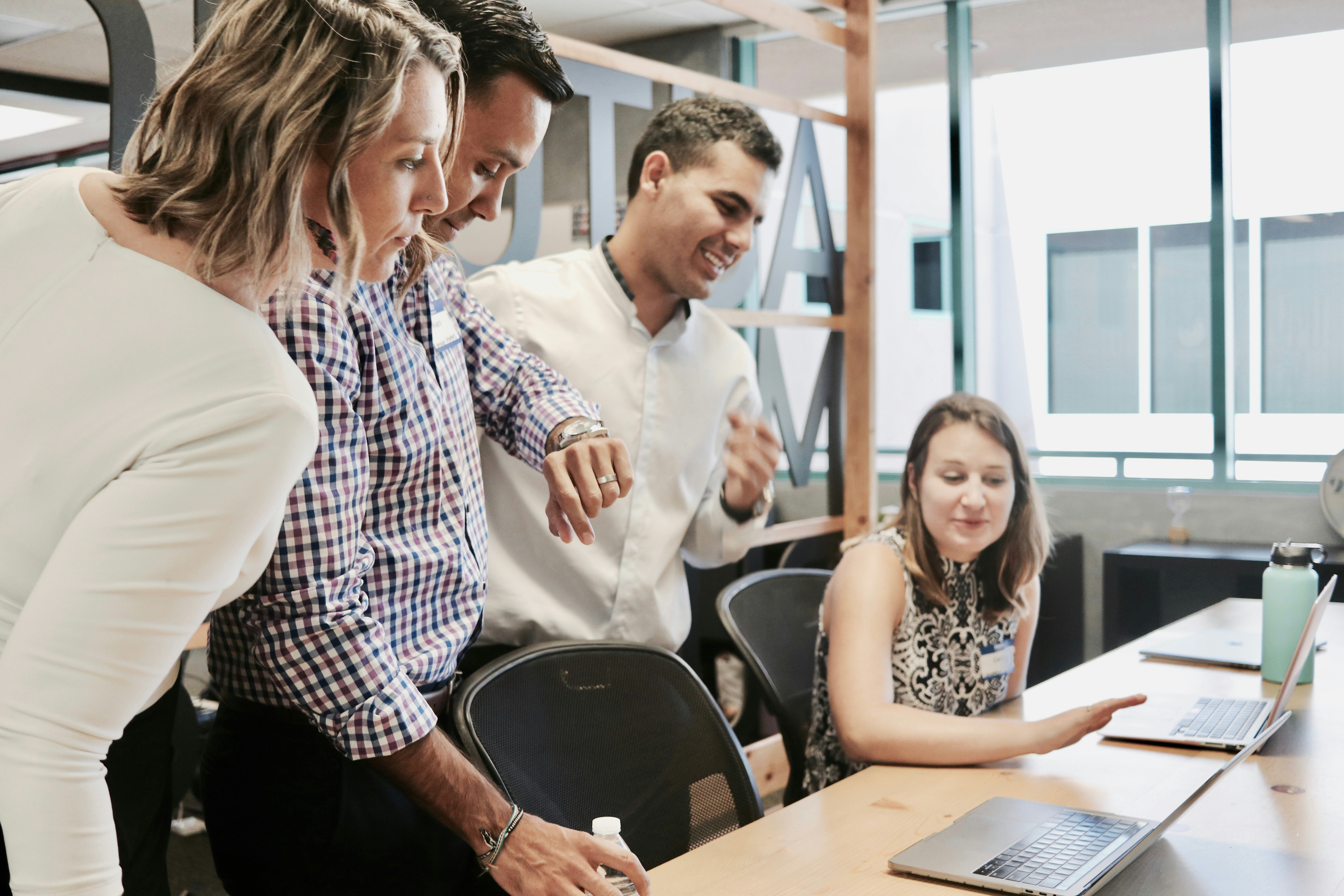 Four colleagues collaborating around a wooden conference table in a modern office.