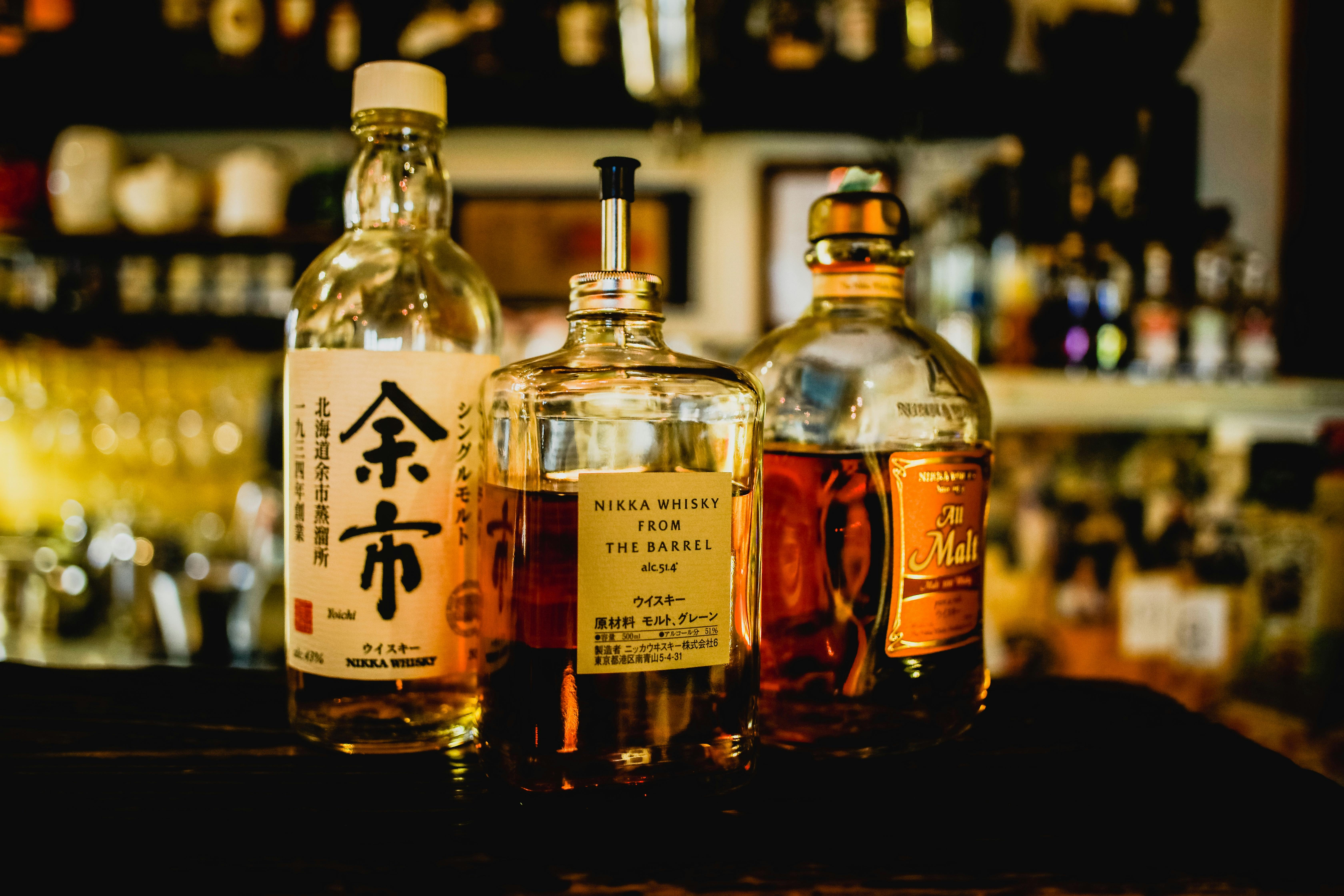 Thhree bottles of alcoholic beverage at the bar.