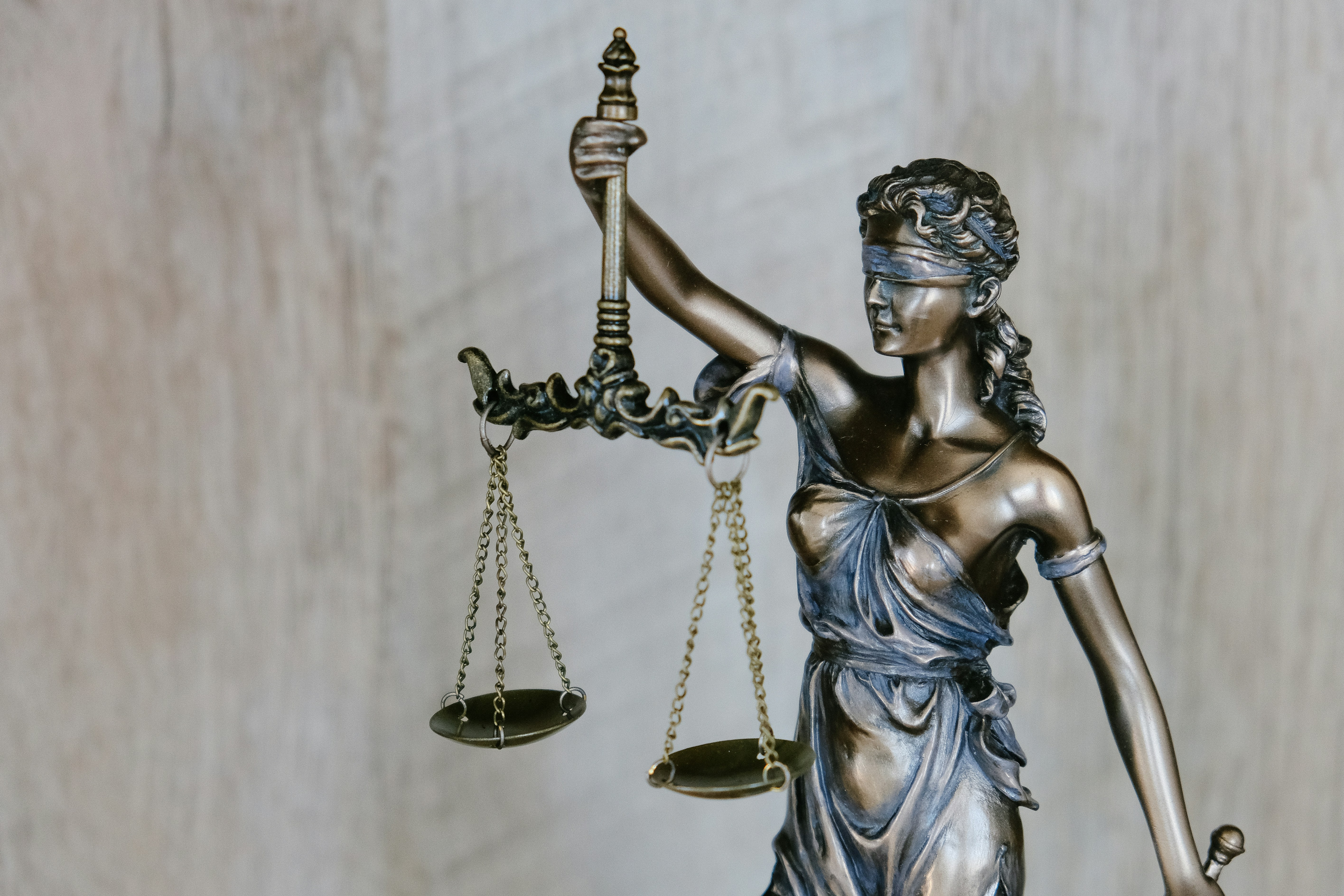 Bronze statue of Lady Justice holding balanced scales in her left hand, symbolizing fairness and impartiality in law.