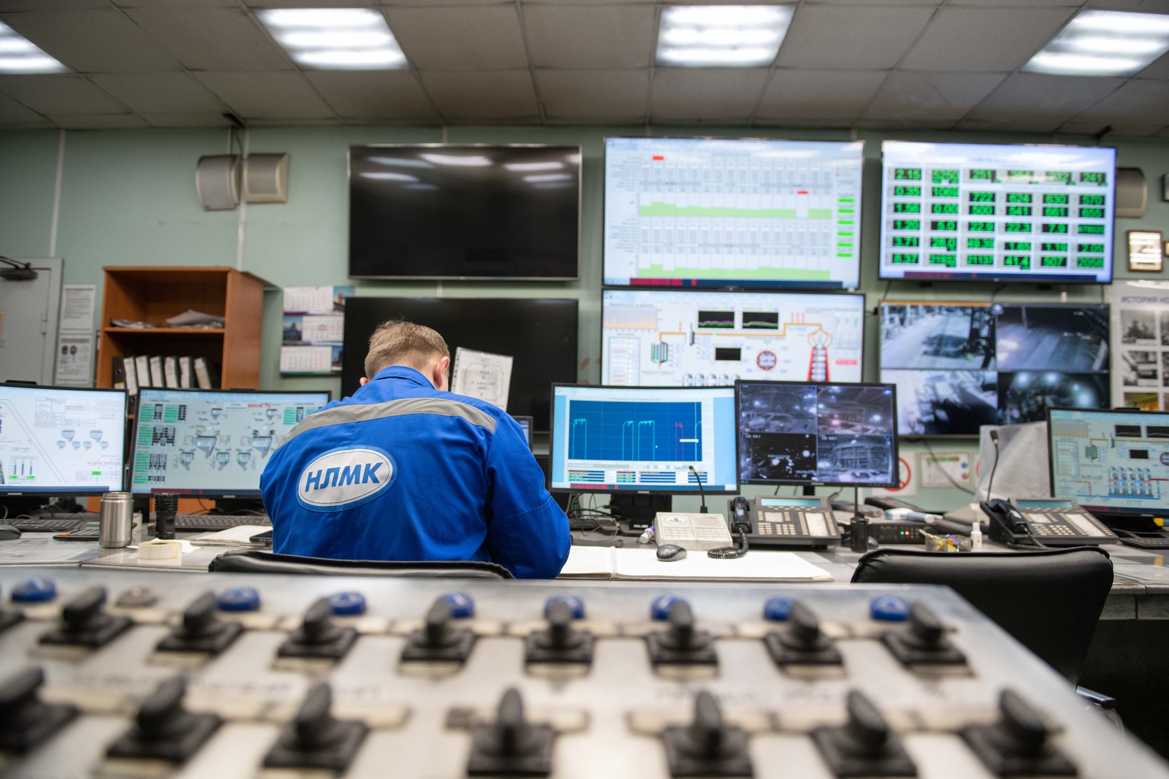 Engineer monitoring a wall of process control screens