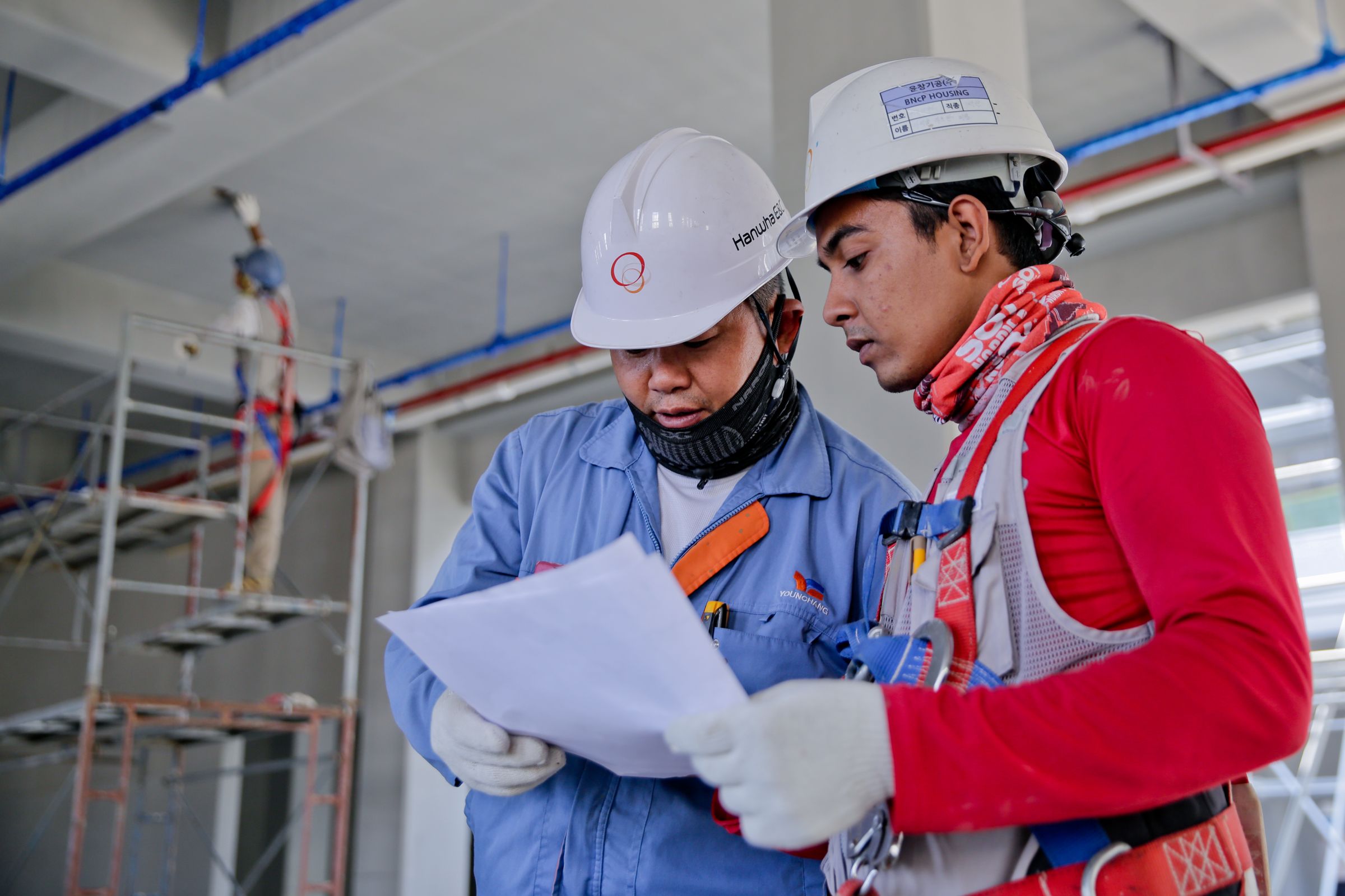 Two engineers in hard hats reviewing documents on site