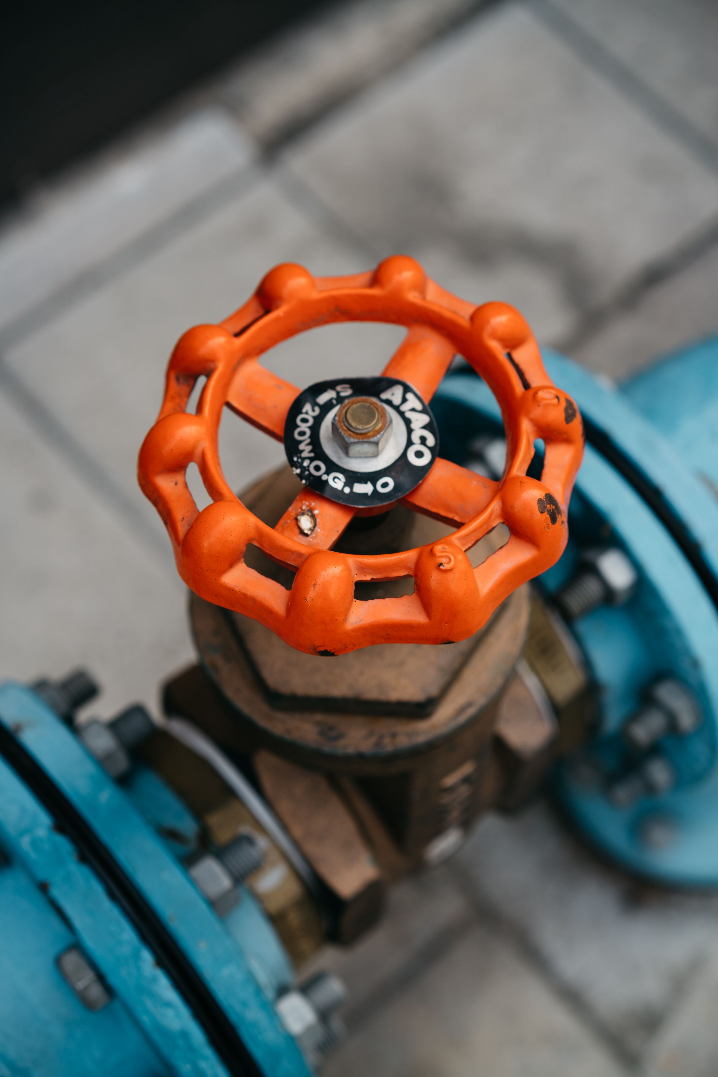 Close-up of an orange valve wheel on an industrial pipe